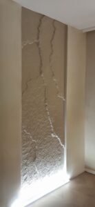 Bézs árnyalatú 3D Fillit sziklafal Led világítással egy modern budapesti hálószobában – kézzel formált textúra, egyedi lakberendezési megoldás privát és üzleti terekhez Budapesten, Győrben, Debrecenben és Pécsett - kivitelezés.