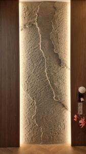 3D Fillit sziklafal dekoráció modern hálószobában: függőleges elrendezésű, kézzel formált bézs kőhatású fal meleg oldalsó súrolófényekkel.