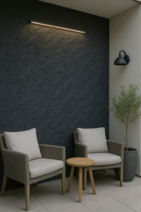 Modern kültéri pihenő két fotellel, antracit színű struktúrált pala falburkolattal, meleg LED világítással kiemelve.